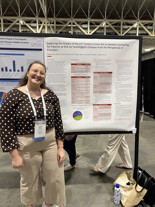Abby stands to the left of her poster. She is wearing a polka dot shirt and smiling.