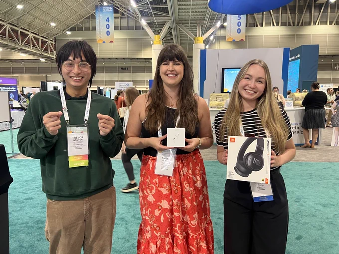 Trevor, Amber, and Katie hold up their prizes and smile.