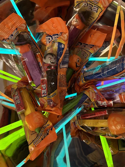 Bowl of PEZ candy with Halloween character dispensers and glow in the dark sticks ready for treating tricksters.