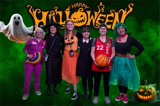 Group of six people in Halloween costumes with ghost and pumpkin decorations.
