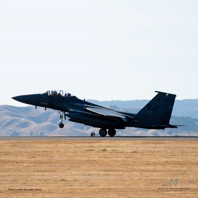 Picture of an F-15E fighter jet taking off, with rolling hills in the background.