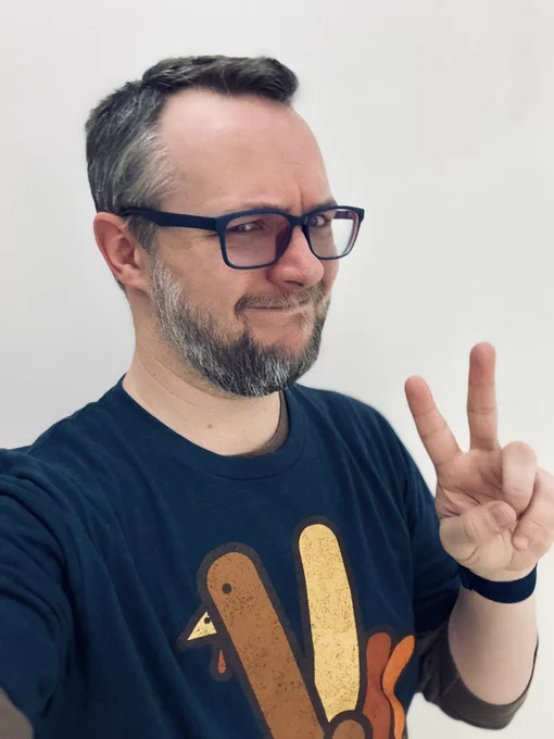 Me in a T-shirt with a turkey shaped like a hand giving a peace sign while I also give a peace sign.