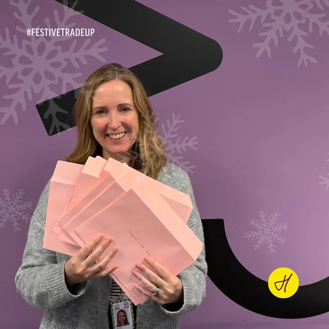 Lucy Parish, Hopestead's Head of Operations,  poses with the pink envelopes containing the £10 to kickstart teams on their fundraising challenges