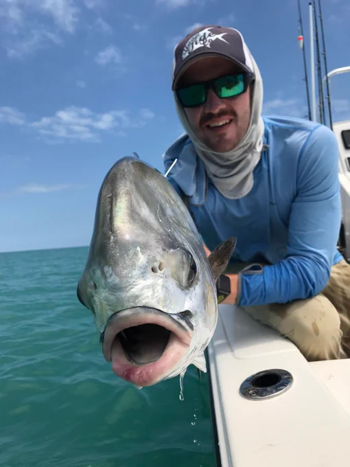 A photo of Dr. Jake Brownscombe holding a permit (Trachinotus falcatus)