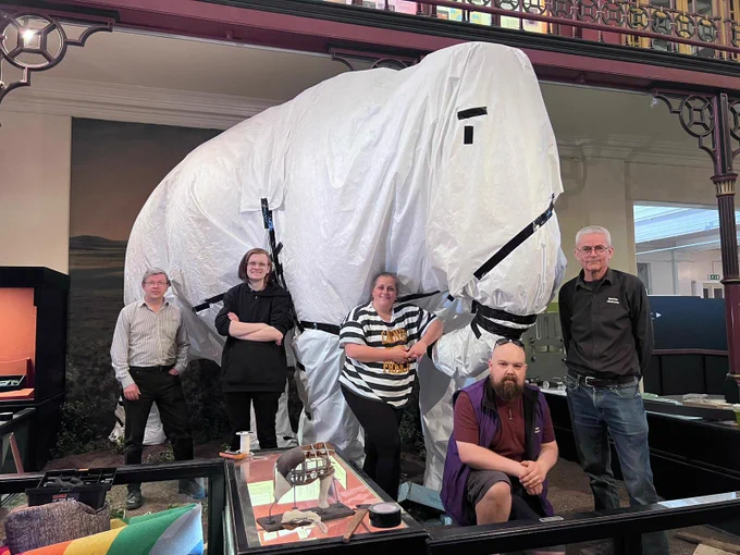 Five museum staff members pose in front of the mammoth which has been wrapped to protect it during the redevelopment project. 