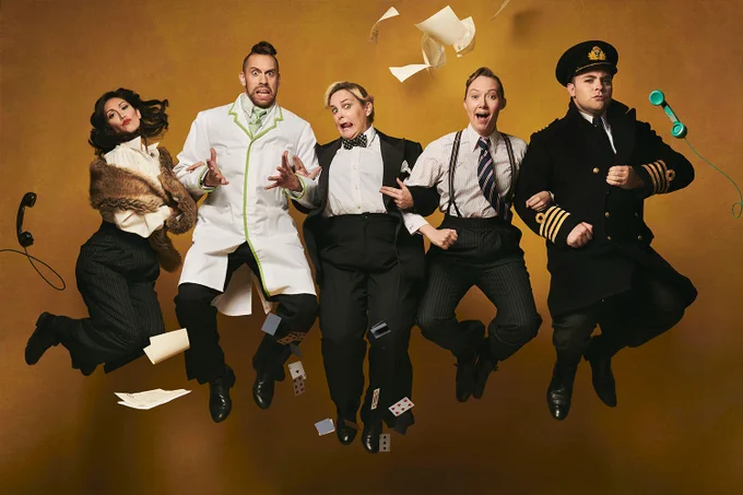 A photo showing five individuals jumping in vintage outfits, stood in front of a faded yellow background