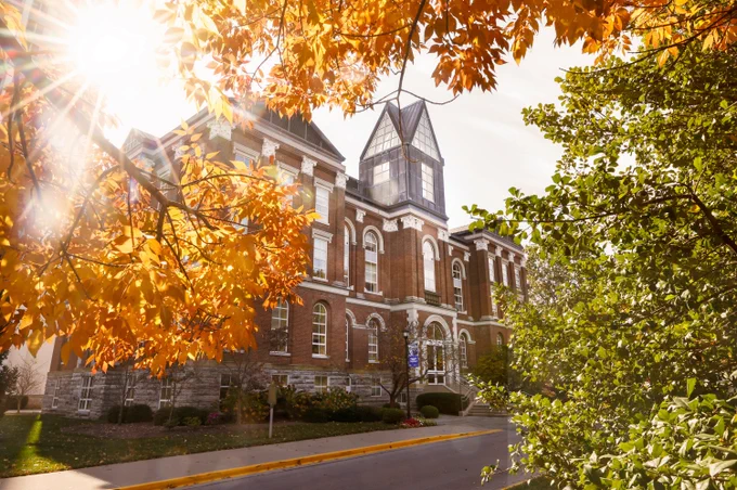 Autumn leaves frame the sunlit facade of the Main Building at the University of Kentucky