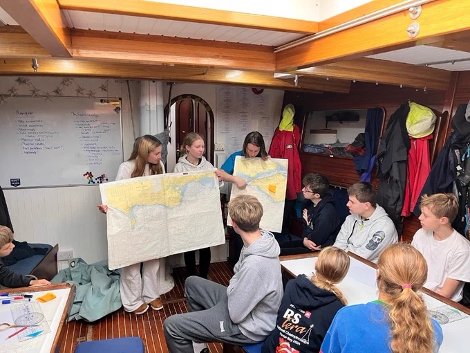 Three crew members hold up charts while the others watch