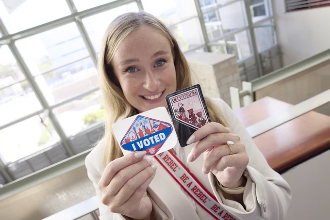 Person holding two "I VOTED" stickers in a Lied Library.