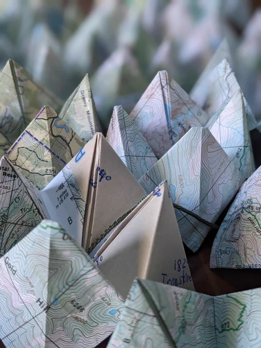 Trail Mix, 2024, by Allison Arth. A close-up of a field of origami fortune tellers made from trail maps.