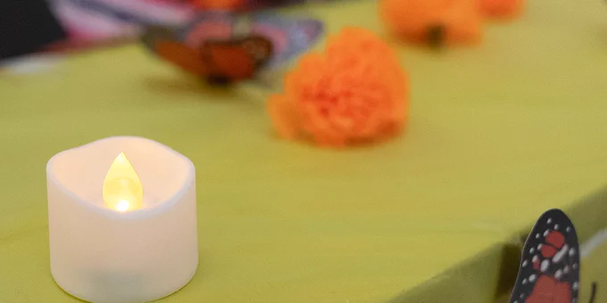 Candles and flowers can be seen in a closeup of the decorations on the community ofrenda on the second floor of the Jacobs School.