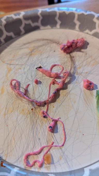 A pile of blond hair on a plate, interspersed with chunks of pink slime.