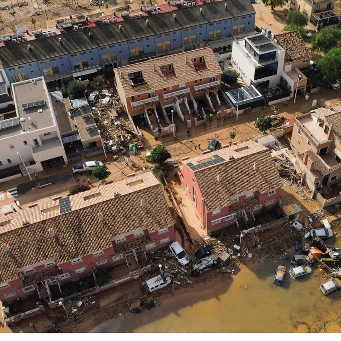 Aerial view of a flooded residential area after a severe rainfall, showing damaged homes and vehicles surrounded by muddy water in Paiporta Spain near Valencia