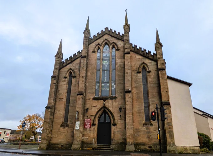 The front of Holy Trinity anD St Barnabas In Paisley. A blonde sandstone church witha peaked roof