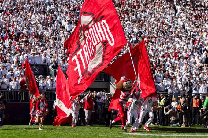 Brutus and others run onto the field with the Ohio State flag.