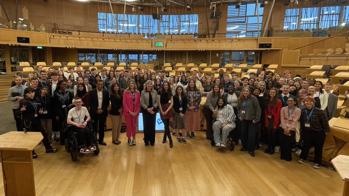 Members of the Scottish Youth Parliament, Foysol Choudhury MSP and Alison Johnstone MSP, Presiding Officer of the Scottish Parliament standing together on the floor of the Parliament debating chamber.