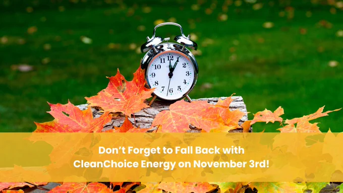 Promotional image featuring an analog alarm clock set at 2 o'clock on a log surrounded by autumn leaves, with a reminder to adjust time for 'Fall Back' with CleanChoice Energy on November 3rd.