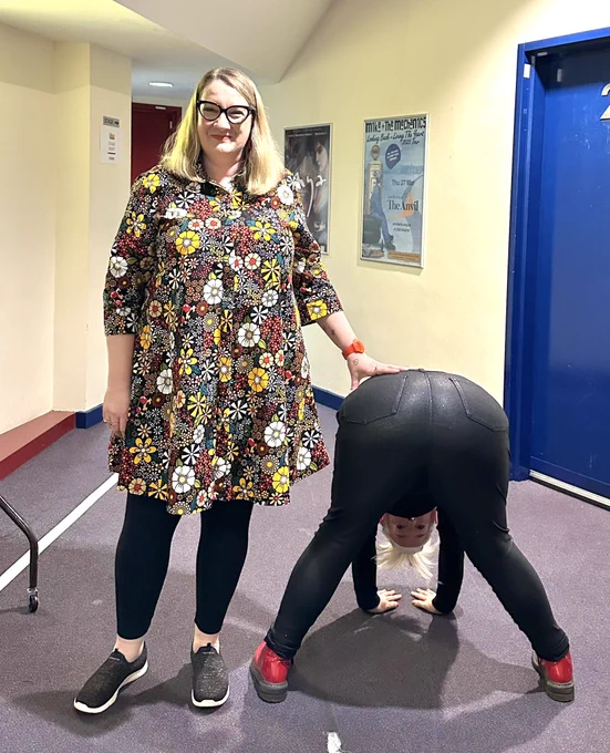 I’m on the left I’m a multicoloured flowery Zuri dress, black leggings and black sparkly trainers. On the right is Lou with her back to us, bent over, hands on the floor and wearing lovely black sparkly jeans and red boots. She is looking through her legs at us.