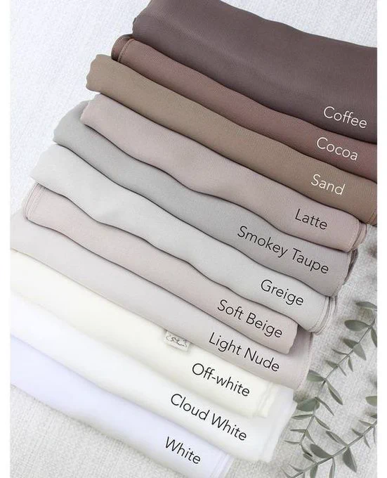 Stack of folded fabrics in various neutral shades from dark to light, labeled from top to bottom as follows: Coffee, Cocoa, Sand, Latte, Smokey Taupe, Greige, Soft Beige, Light Nude, Off-white, Cloud White, and White. The fabrics are neatly arranged to display the subtle gradient of earthy tones, highlighting a spectrum of beige and cream colors.

