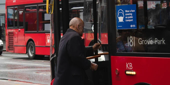 A man stepping onto a red bus.