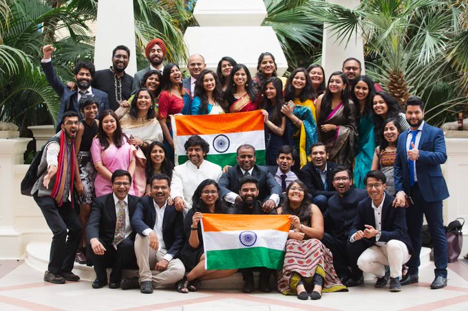 Previous recipients of the scholarships surrounding two India flags in a group shot, in front of a leafy green background. Image credit - 
Imperial College London