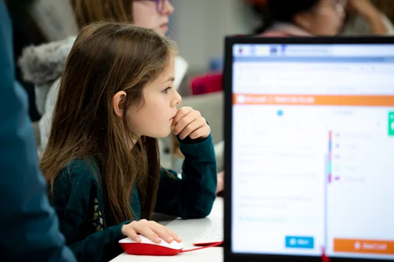 Photo of a young person sitting at a computer, concentrating on their work.