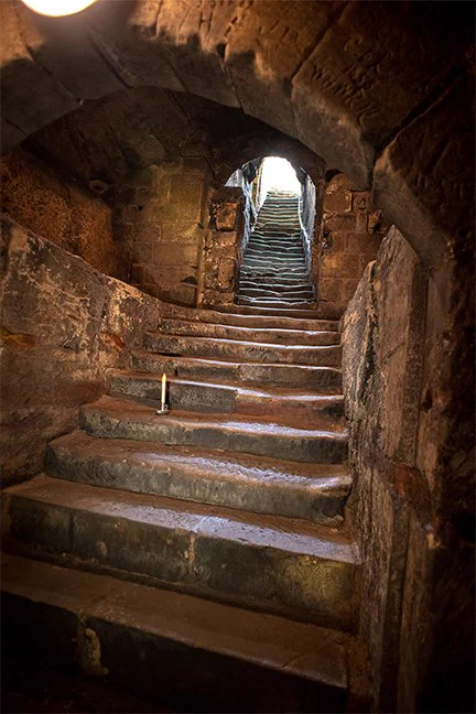 The historic steps leading up out of the Pontefract Castle dungeon, with some of the centuries-old graffiti visible in the archway stones.