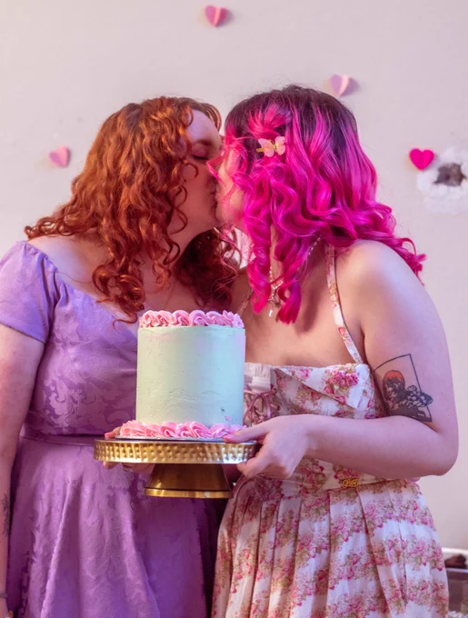 ru and jeffie having a smooch holding a green and pink cake in front of them