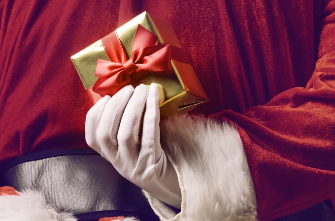The back of Santa, hiding a gold wrapped parcel behind his back.