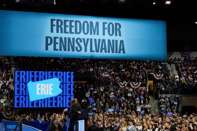 An image of Vice President Kamala Harris standing at a podium at a campaign event in Erie,  Pennsylvania. Behind Vice President Harris is a blue sign that reads, "Freedom for Pennsylvania."