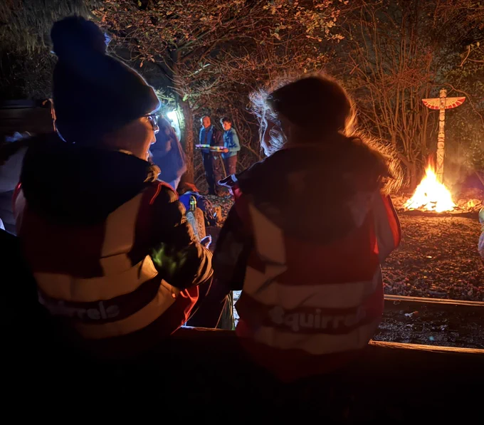Two Squirrel Scouts in front of campfire