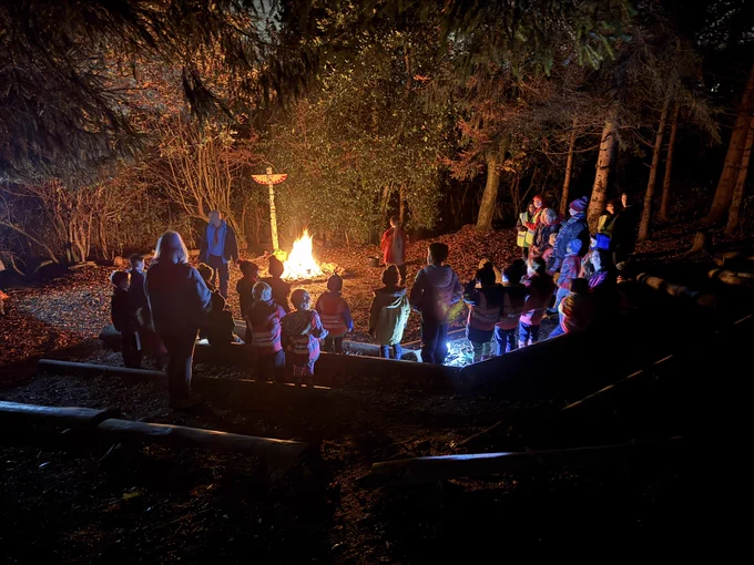 Group of Squirrel, Beaver Scouts and adult volunteers in campfire circle