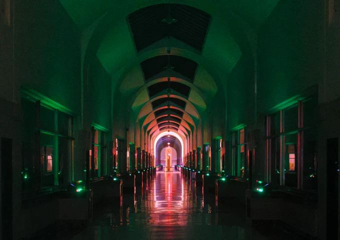 a view down the long marble hallway, lit by green lights on the control panel, with a view of the art deco brass clock in the lit up Rotunda. 
1/15th, handheld. camera pressed against the glass door 