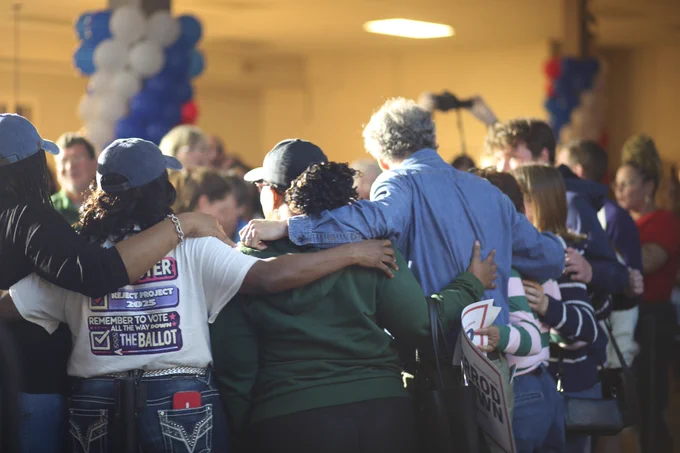 Senator Brown standing with a group of event attendees with their arms around each other. 