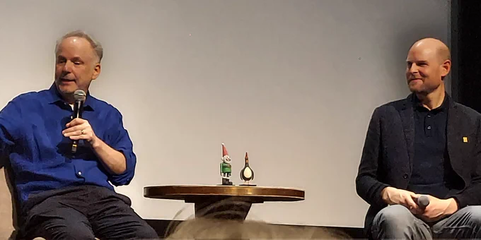 Nick Park, the Norbot Puppet, the Feathers McGraw puppet, and Will Becher on stage. The puppets are on a table.