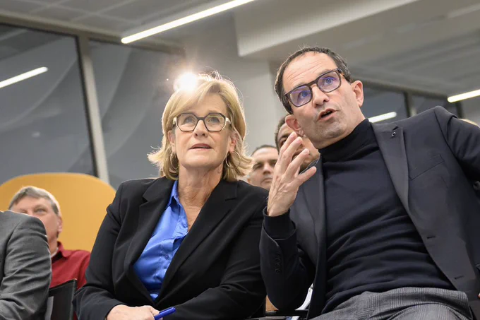 Marie-Agnès Poussier-Winsback et Benoît Hamon assis au premier rang. Ils discutent.