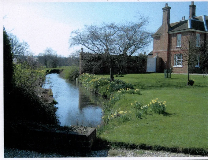 Grade II listed building Ham House can be seen on the right of the photo, surrounded by green grass with daffodils sprouting along the edge of the stream on the left.