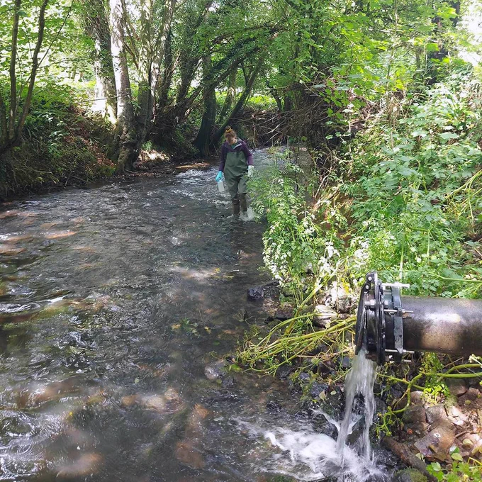 Holly Tipper sampling for environmental AMR in a river near an outflow pipe