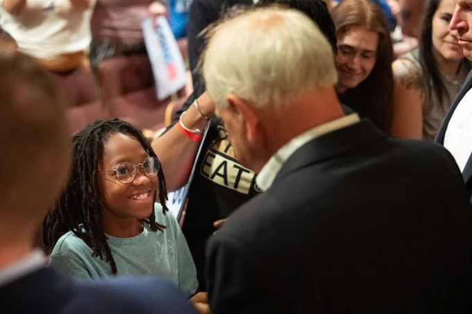 Governor Tim Walz talks to a young supporter at an event.