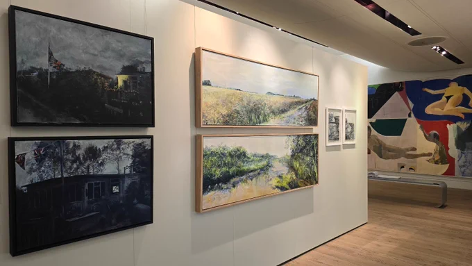 Six artworks on a white gallery wall. On the left are two dark paintings of chalets at night. In the middle are two paintings of salt marshes. And on the right are two black and white drawings. 