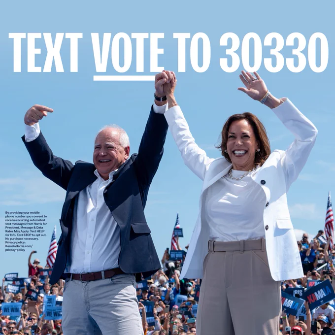 Tim Walz and Kamala Harris celebrating at a rally with arms raised, under a clear sky, with text 'TEXT VOTE TO 30330' displayed above.