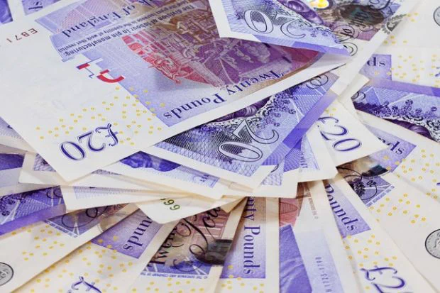 A collection of scattered British pound sterling banknotes in various denominations.
