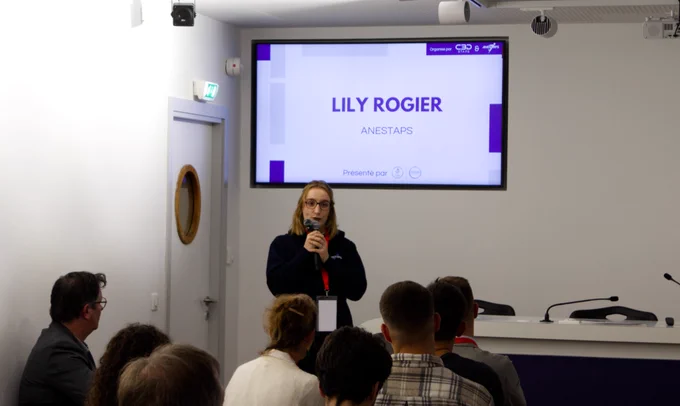 Lily rogier, debout face au public, avec écrit sur l'écran derrière elle, "Lily Rogier, ANESTAPS"