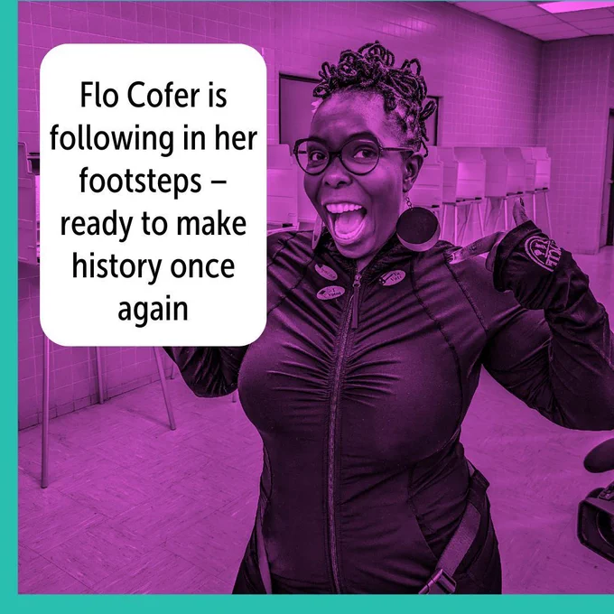 The image shows Dr. Flo Cofer, smiling widely and looking enthusiastic, standing in what appears to be a voting location. She is wearing glasses and dark clothing, with a sticker on her chest. The image has a purple tint. A white text box on the left side of the image reads, "Flo Cofer is following in her footsteps – ready to make history once again." The background is a room with tiled walls and voting booths. The border of the image is teal on the left side.