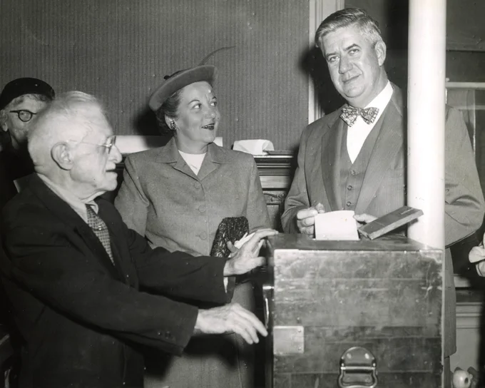Black and white photograph of Tip O'Neill casting his ballot with Millie O'Neill looking on
