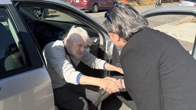 Photo of me bent over to shake hands with a lady sitting in her car.