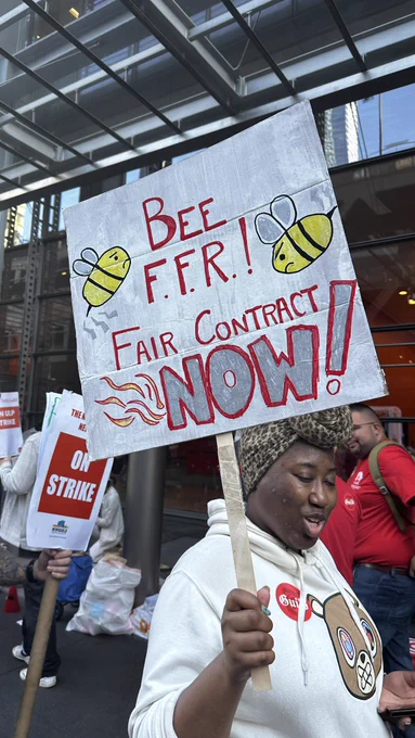Union members holding sign that says “BEE FFR! FAIR CONTRACT NOW!”