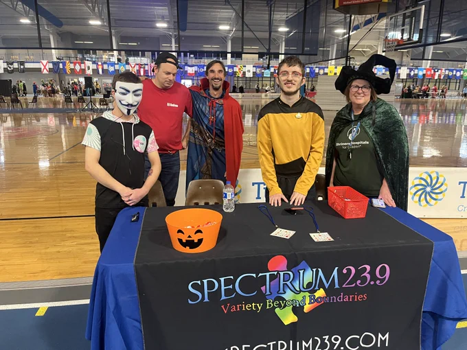 5 people with the Spectrum 23.9 radio station dressed up in costume and handing out candy at their table. 