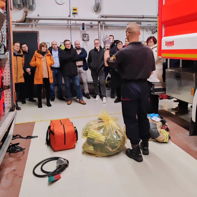 Kurssilaiset kalustohallissa paloautojen takana kuuntelemassa ruiskumestarin opastusta altistumisen vähentämisestä.