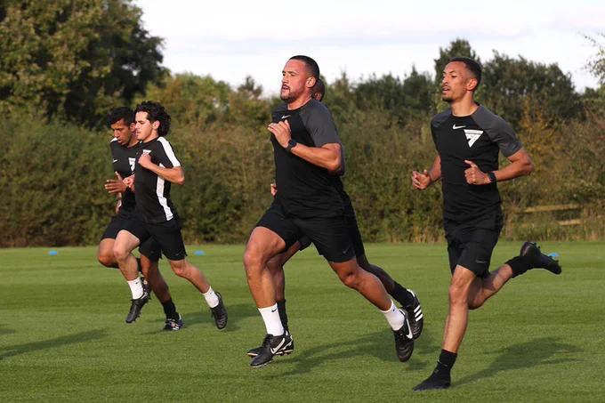 Five PGMOL match officials running on a pitch.